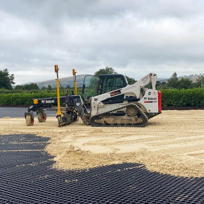 D&C Groundtec installing sand over the grids with a tracked skid steer